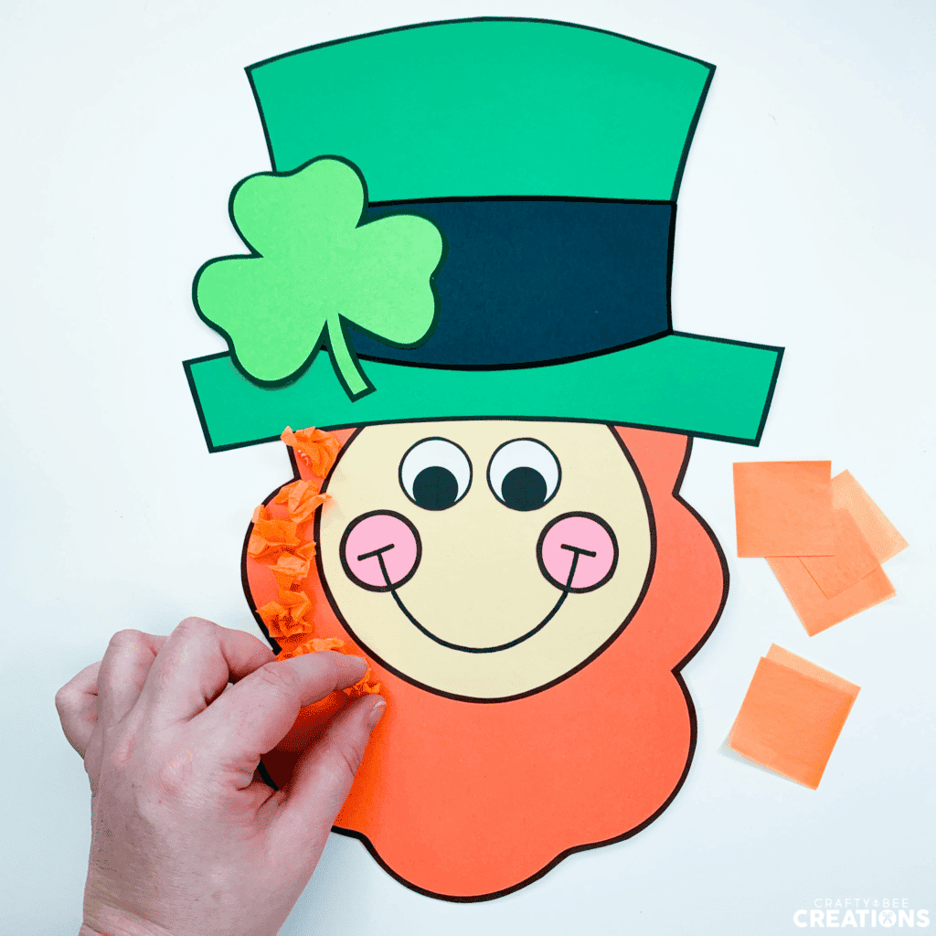 Step four of the leprechaun craft is to glue the tissue paper to the beard and fill in all the spaces.