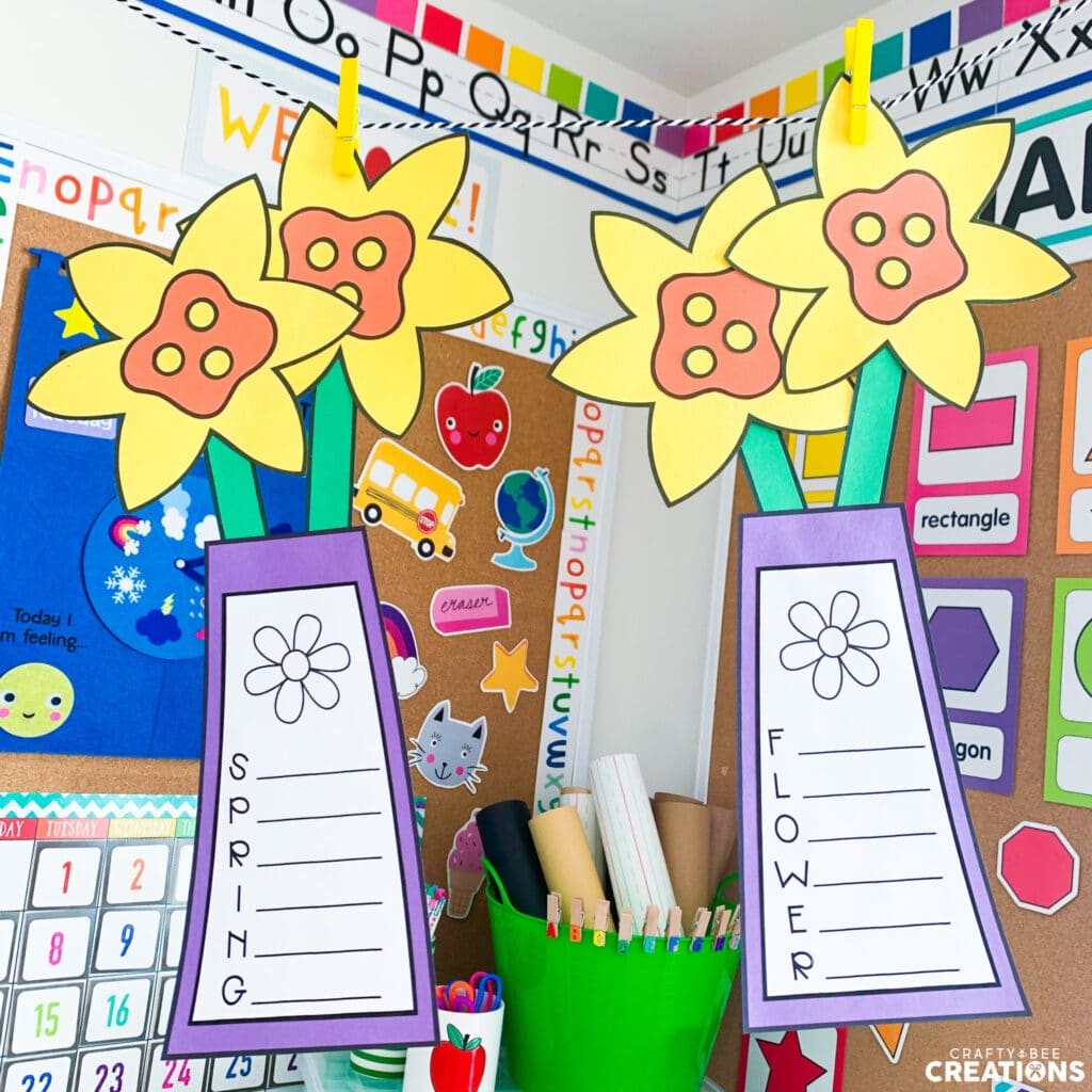 Two daffodil acrostic poem crafts hanging on a string by clothespins. One says SPRING and the other says FLOWER.