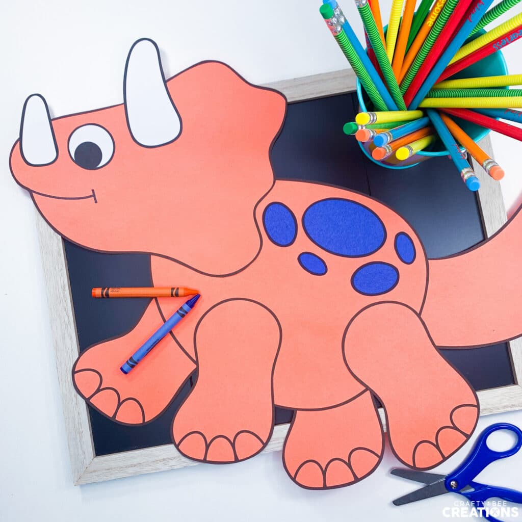 Triceratops dinosaur craft with pencils, crayons and scissors.