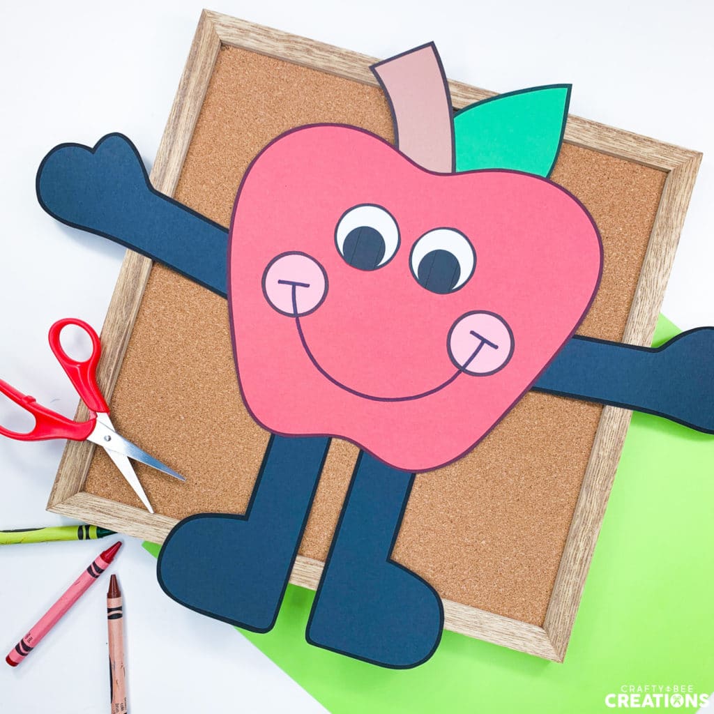 Here is the apple craft on a corkboard with scissors and crayons.